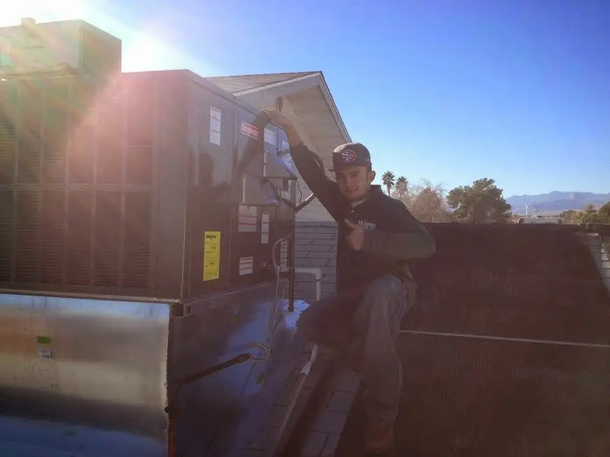 HVAC technician performing HVAC Inspection on a rooftop unit in Rayne