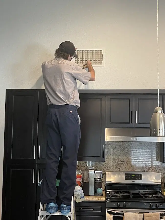 Technician inspecting an air vent during HVAC service in Rayne